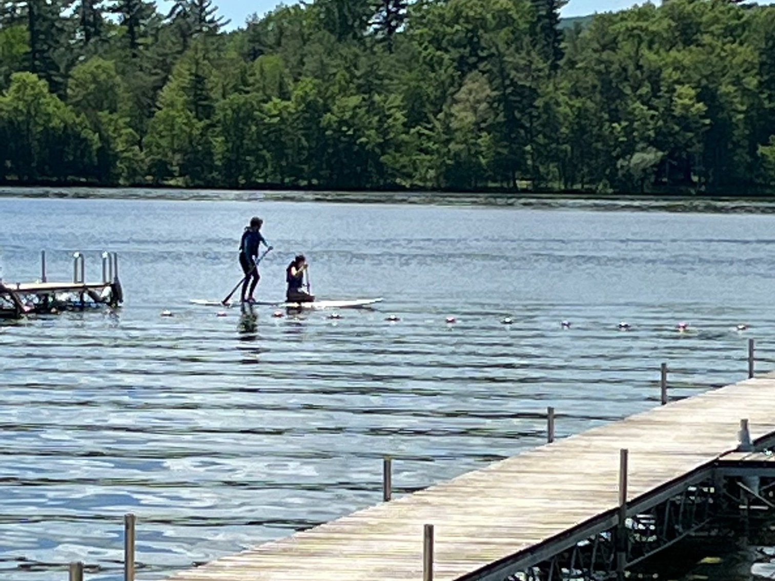 Club boats 2026 Two paddleboarders on East Twin Lake beside the club dock