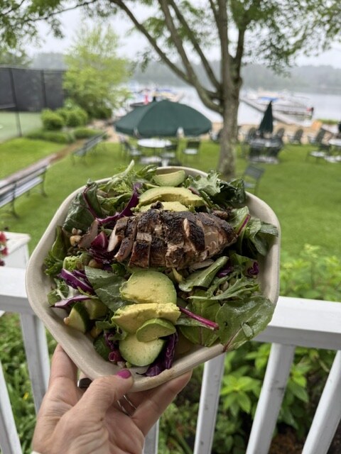 Snack bar salad A snack bar salad with grilled chicken and avocado, held up over the lawn and lake